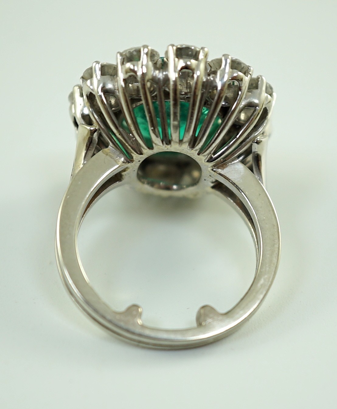 An impressive platinum, emerald and diamond set oval cluster dress ring